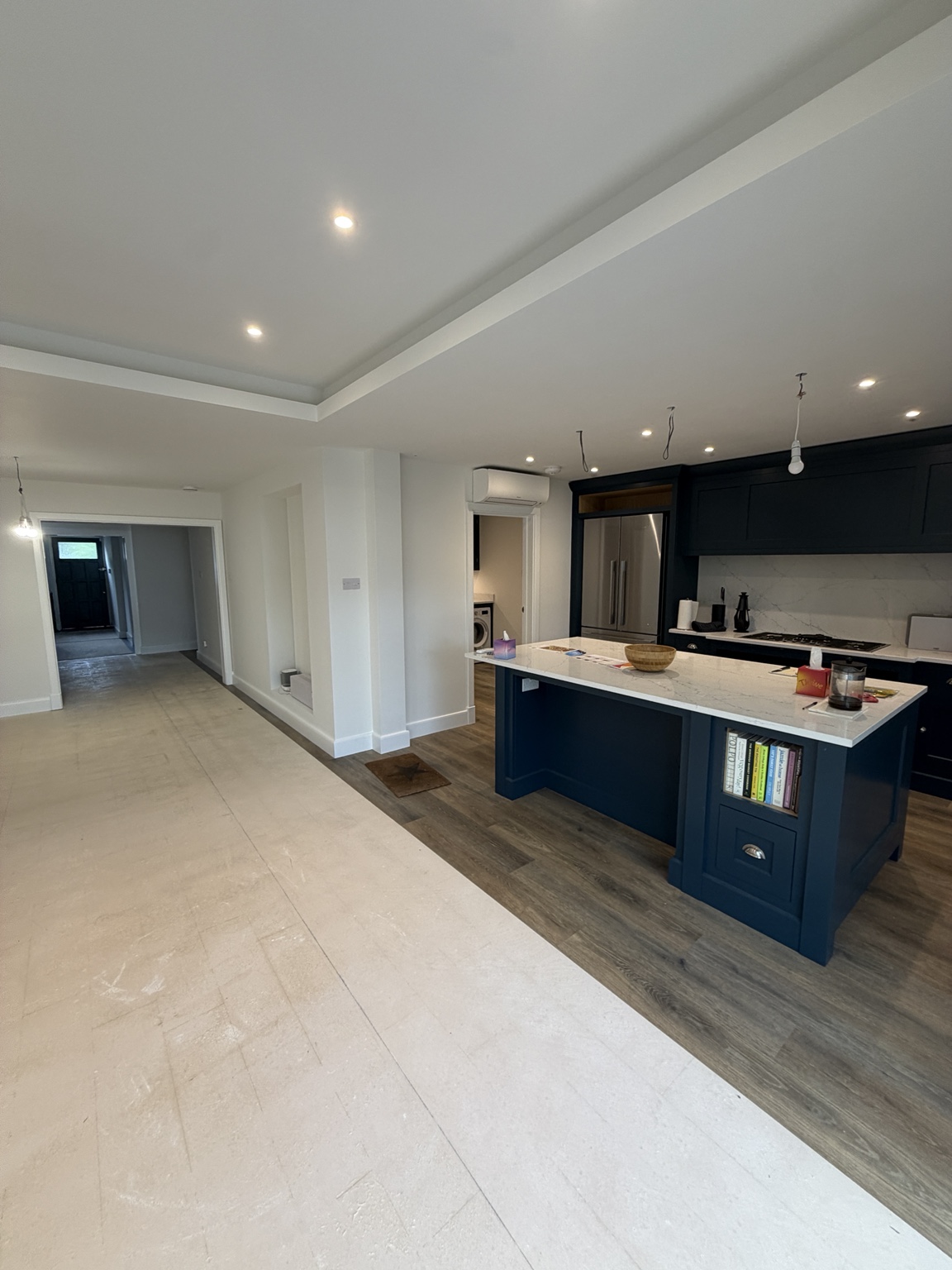 Light neutral kitchen and dining space with white ceilings and navy cabinetry