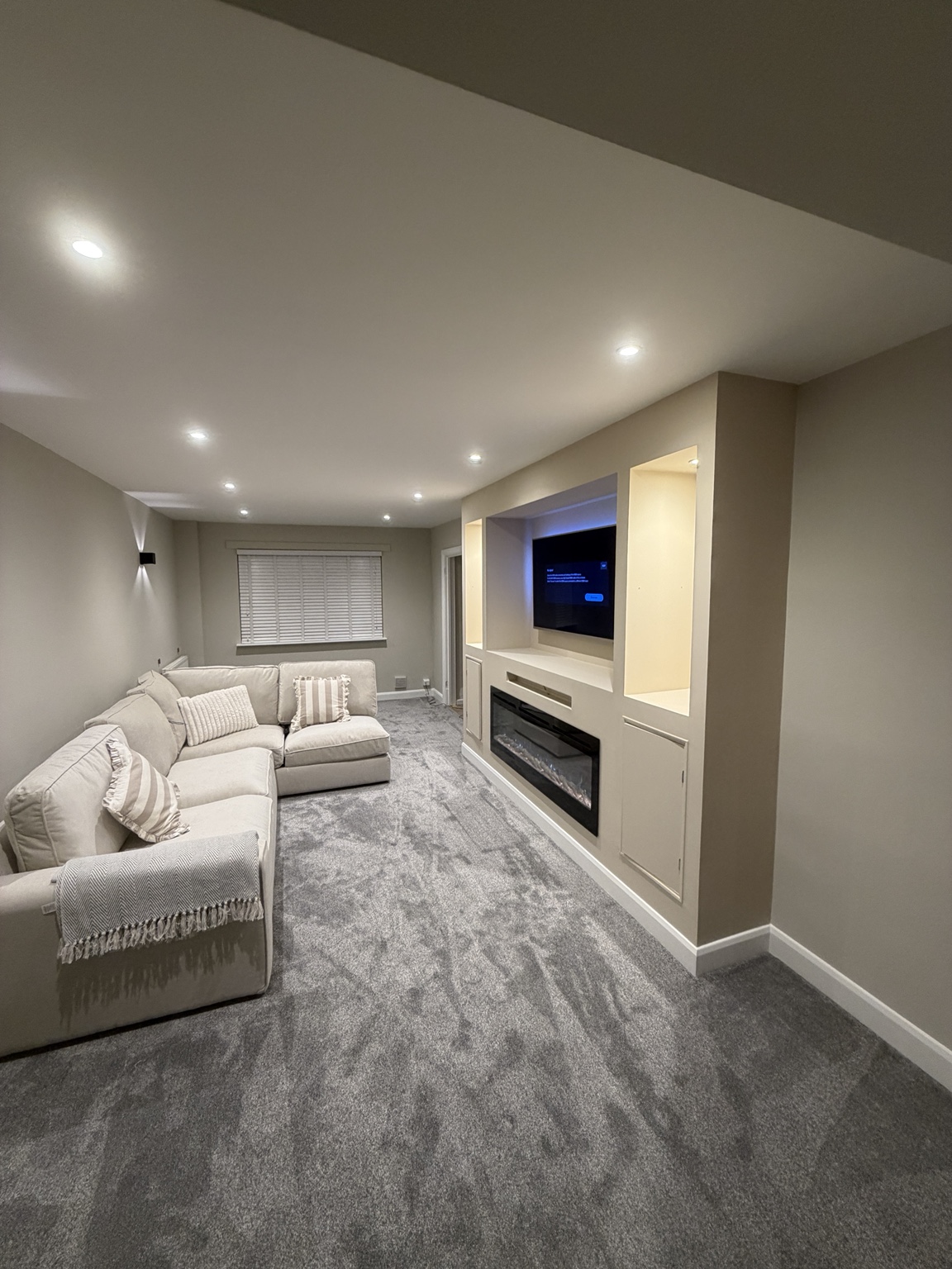 Finished living room decorated by BMH with warm neutral walls, white ceiling and a media wall