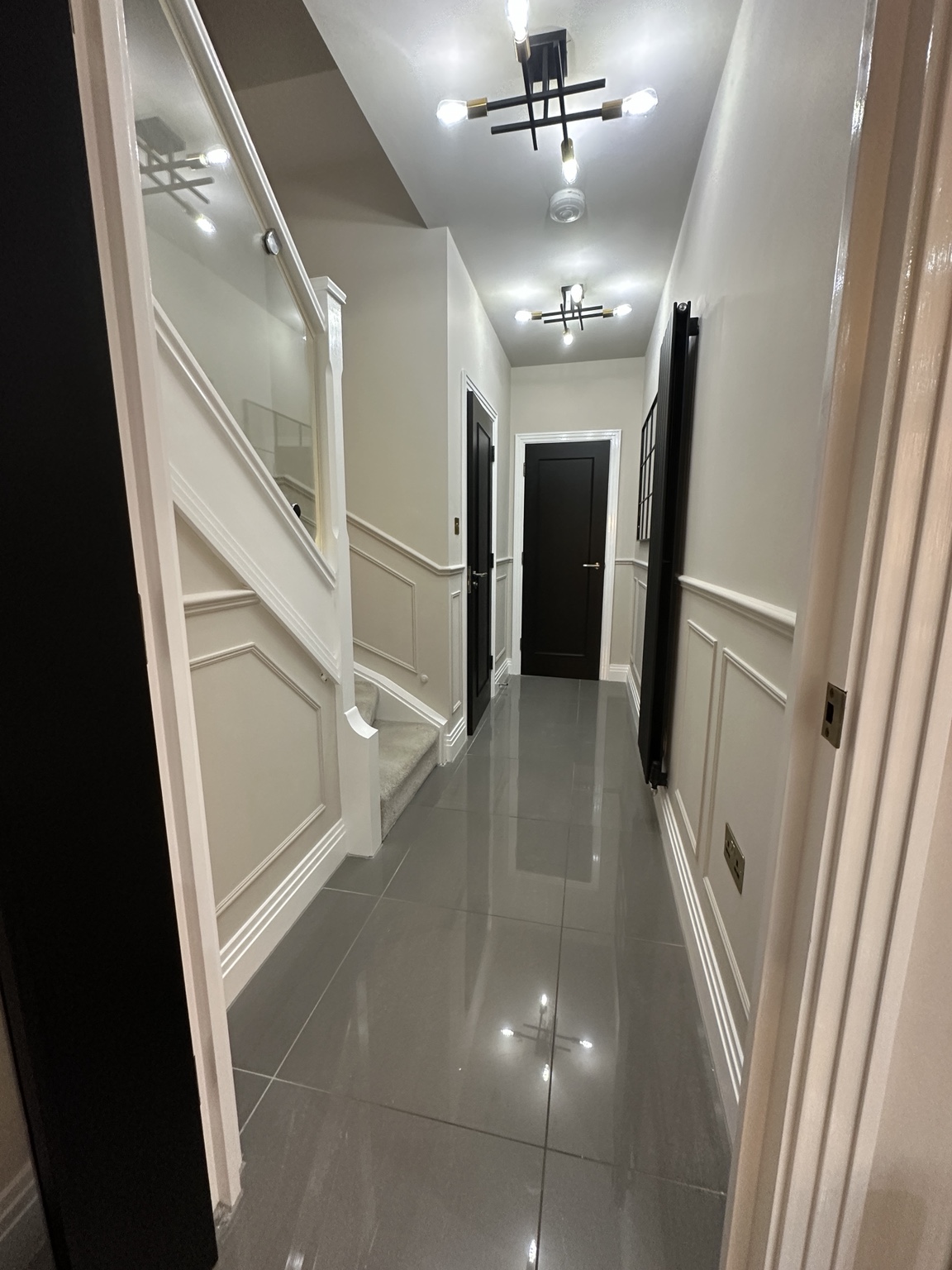 Finished hallway with pale decorative wall mouldings and dark doors